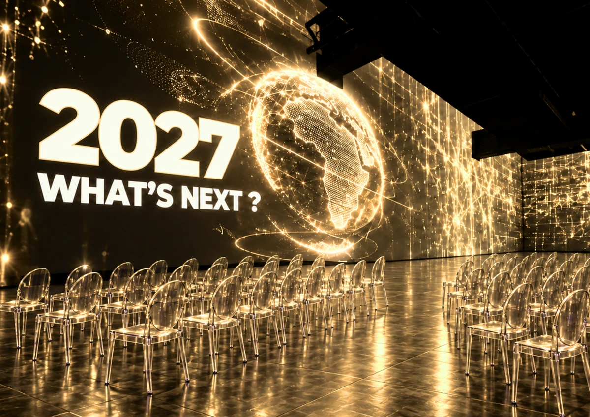 Sala MINA pregătită pentru What's Next 2027: proiecții aurii cu globul pământesc pe pereți și scaune transparente pe podeaua lucioasă.